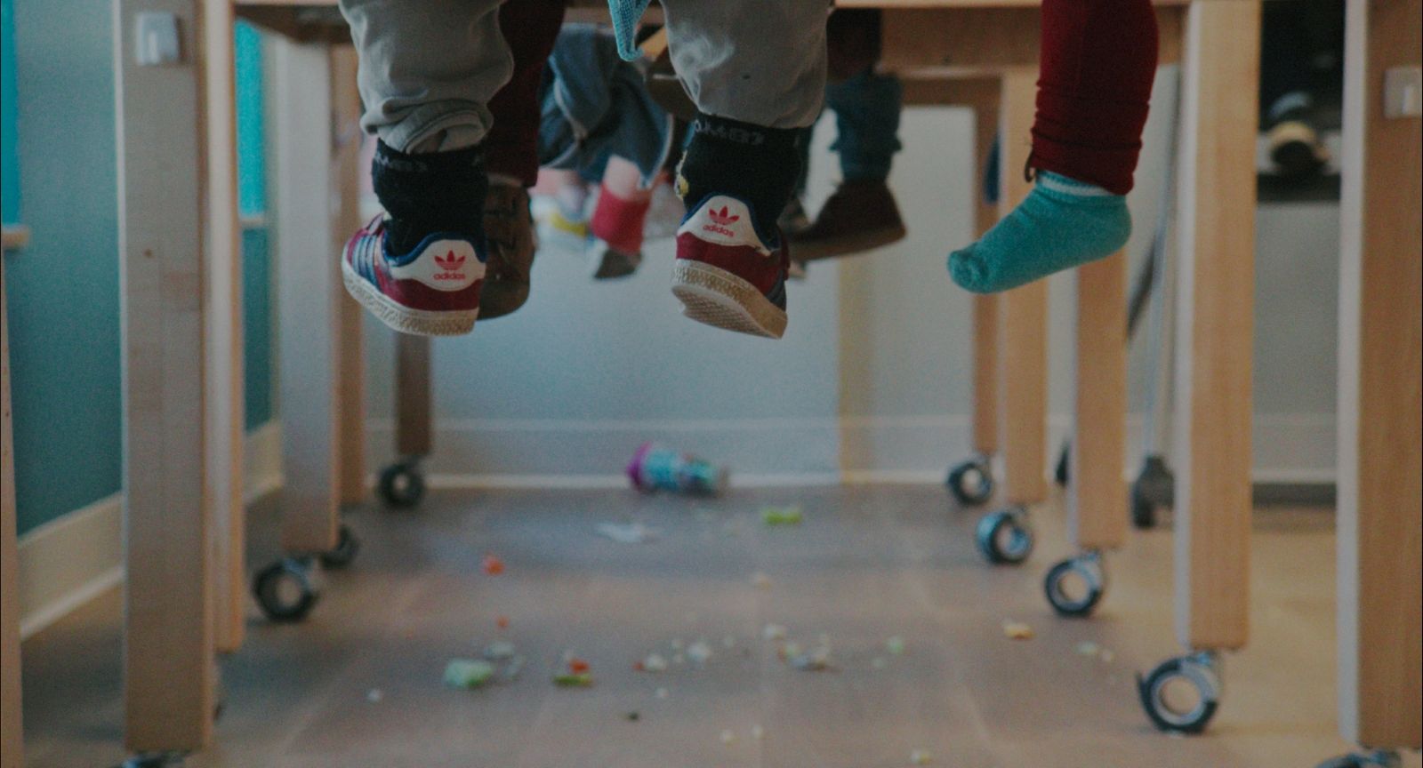 children's legs dangle beneath their desks in a classroom.