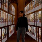 A woman stands surrounded by images of dating app profiles of various men. She looks overwhelmed.