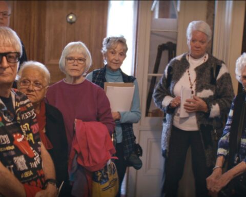Seven senior citizen stand in a semi-circle facing the camera.