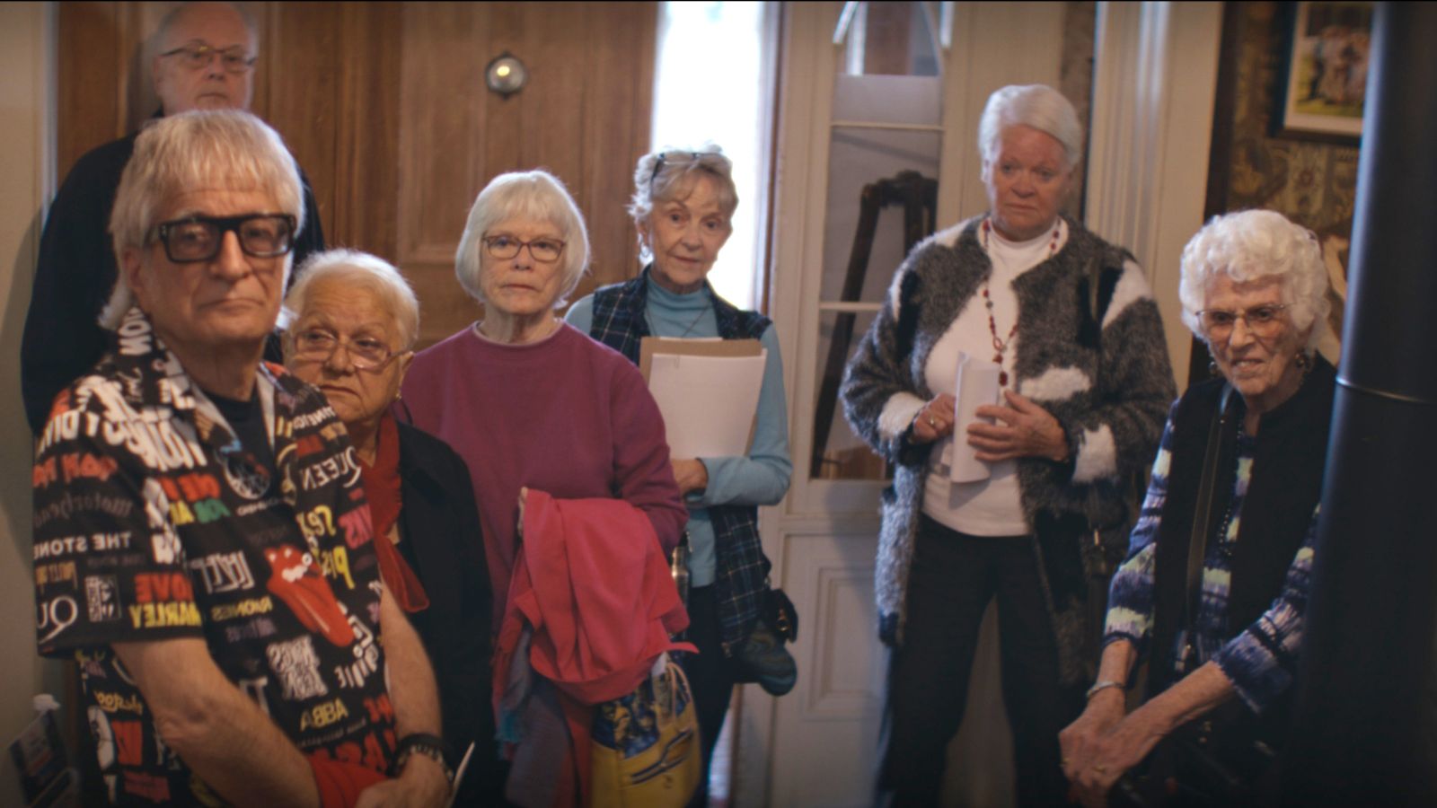 Seven senior citizen stand in a semi-circle facing the camera.