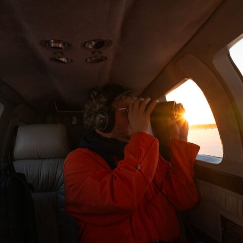Sea-Watch volunteer Matthias looks through binoculars spotting for migrant boats on board the SeaBird 2.
