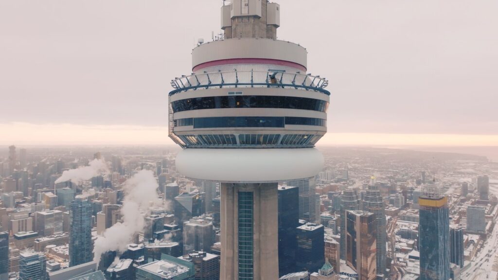 A close-up view of the top of the CN Tower. It is a cloudy day towards sunset.