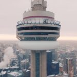 A close-up view of the top of the CN Tower. It is a cloudy day towards sunset.