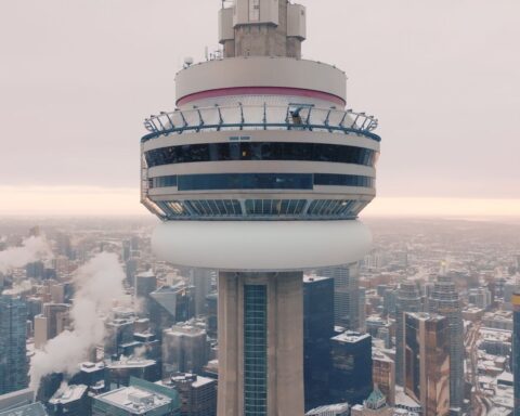 A close-up view of the top of the CN Tower. It is a cloudy day towards sunset.