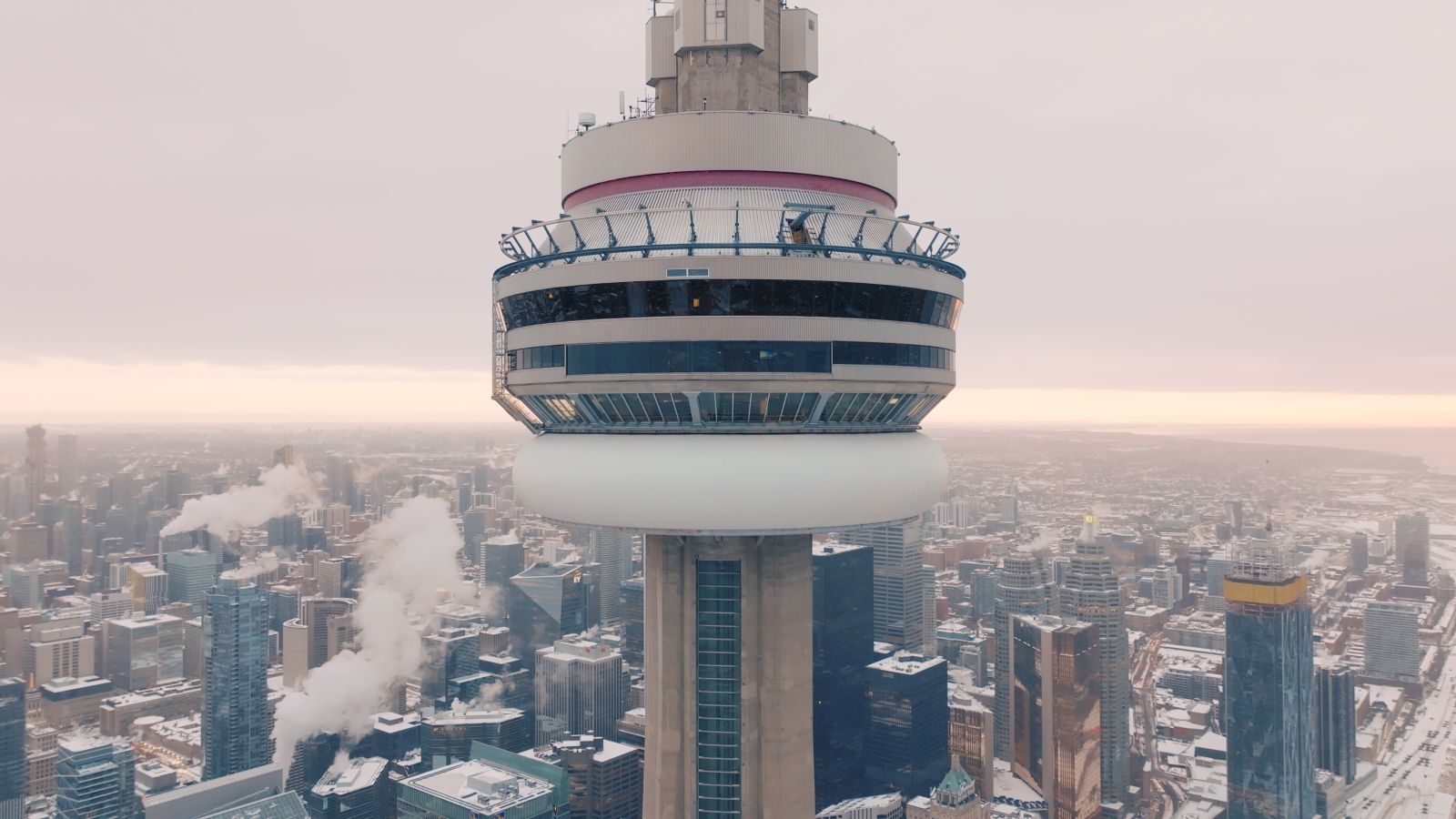 A close-up view of the top of the CN Tower. It is a cloudy day towards sunset.