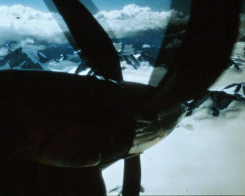 A view down the propeller of an airplane, which is flying over mountains.