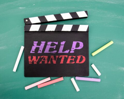 Help Wanted Message on Movie Clapperboard with Chalk on Green Blackboard Background stock photo