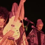 A musician in an Iranian punk bank holds his guitar up in the air.