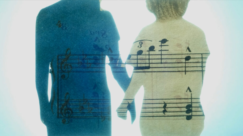 An animated image shows two people holding hands. They are superimposed atop the bars and notes of sheet music.