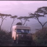 An archival photo of a white Land Rover with the words Grizzly Torque painted in black sits parked in an African safari at dusk.