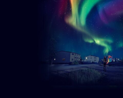 A nighttime image shows the northern lights with ripple through the sky like a Pride flag