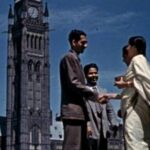 An archival image shows a group of people standing in front of Parliament Hill in Ottawa. The shot is from a low angle as it observes the people talking and shaking hands as the Peace Tower looms behind them.