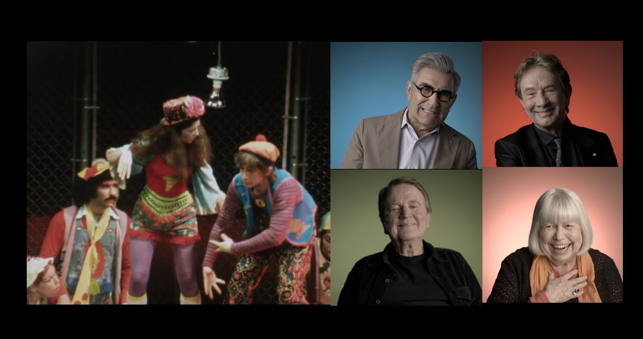 A splitscreen image shows an archival image of a 1970s stage production on the left. There are actors crouched together wearing colourful hippie costumes. On the right side, the screen is split into quadrants with four actors giving interviews with a different coloured background, going clockwise as red, yellow, green, and blue.