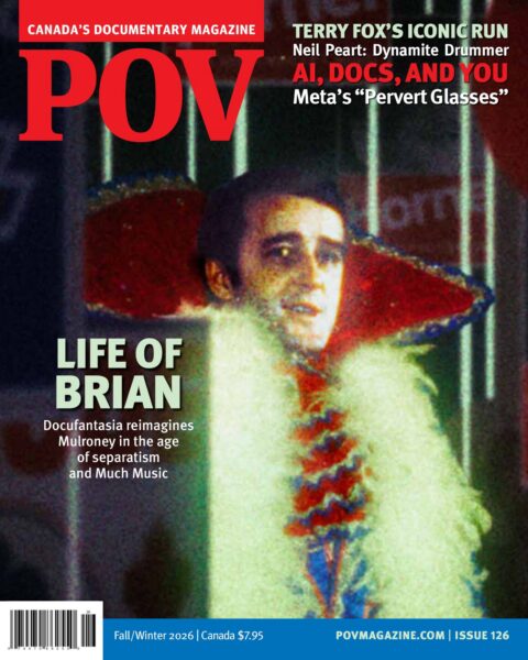 Prime Minster Brian Mulroney appears in a fantastical image. He is pictured from the waist up wearing a flamboyant Liberace-style coat. There is a dazzling background behind him with campaign signs. He looks pale and a bit like a vampire.