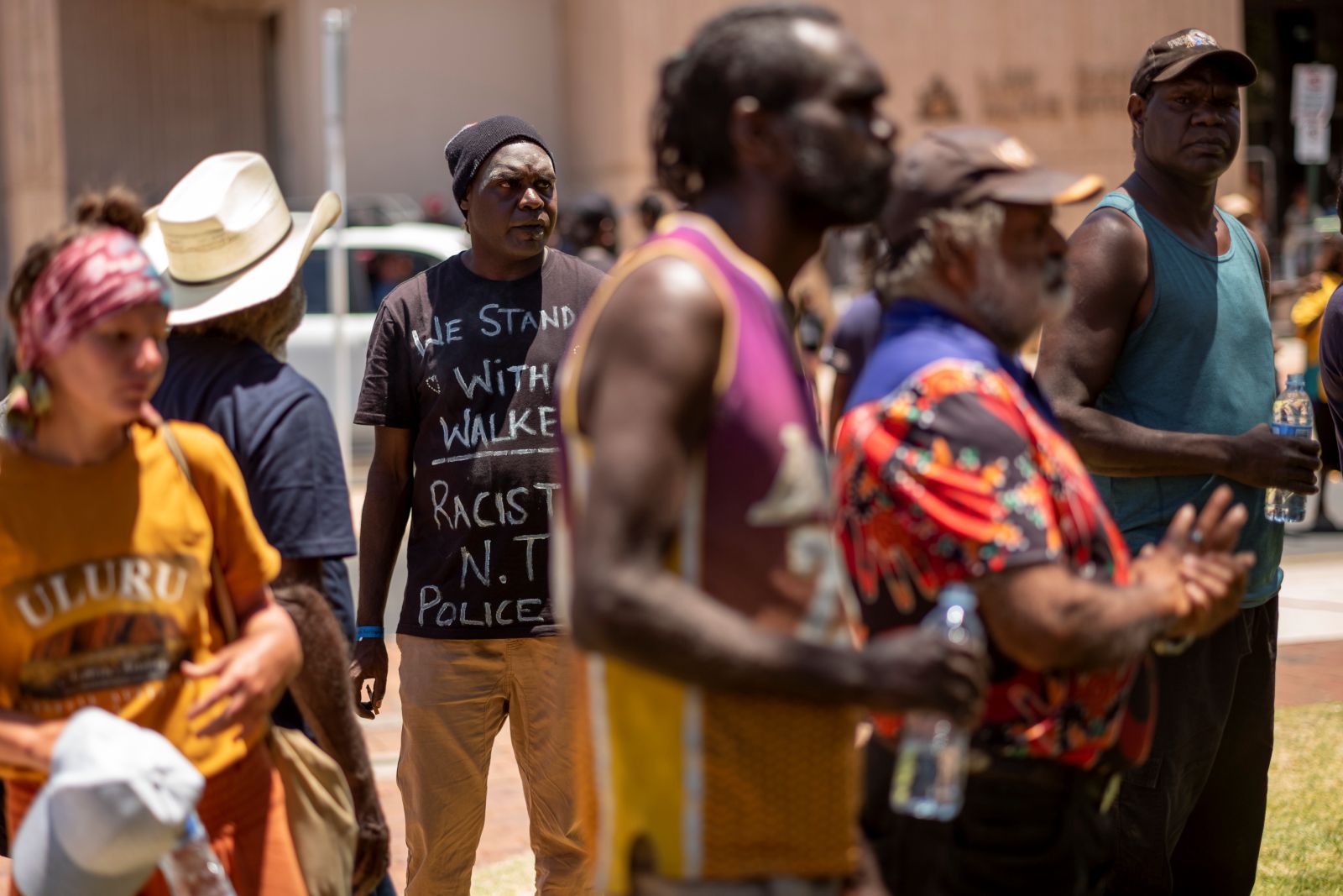 A crowd of Indigenous people in Australia stands together looking anxious and worried. 0............................................................/;;;;;',llllllllllllllllllllll