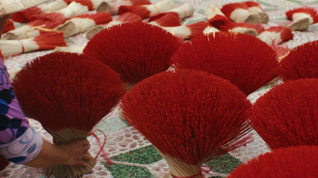 Bundles of Vietnamese incense sticks rest fanned out and upside down with the red-dyed tips up in the air.