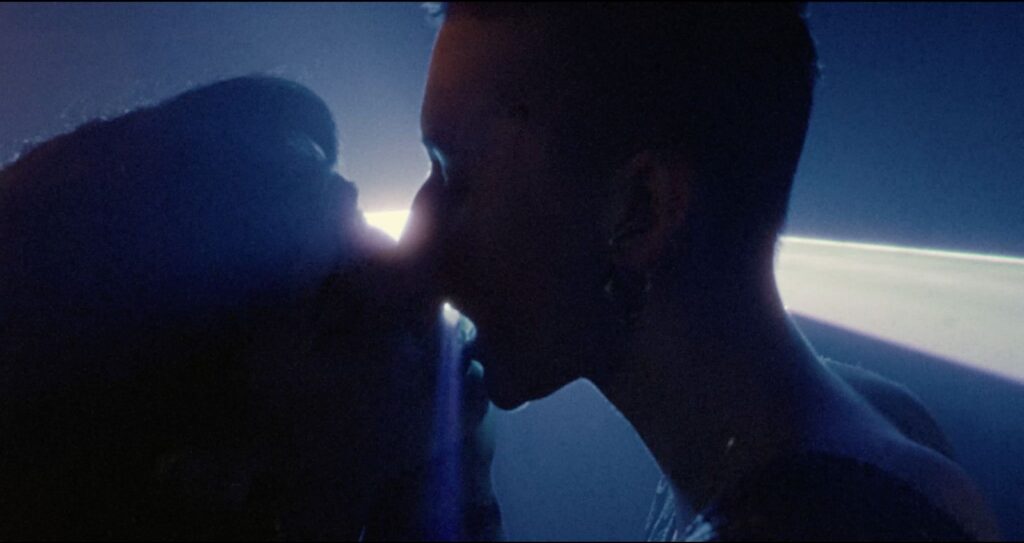 A silhouette shows the image of two people kissing on the dance floor. They are in close up and there is a spotlight behind them.