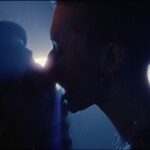 A silhouette shows the image of two people kissing on the dance floor. They are in close up and there is a spotlight behind them.