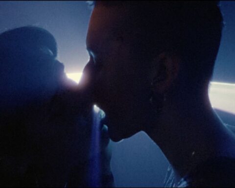 A silhouette shows the image of two people kissing on the dance floor. They are in close up and there is a spotlight behind them.