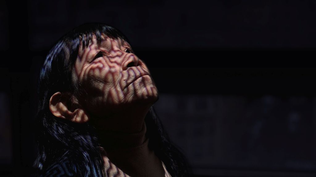 A close up on shows a pattern of lines in shadows across the face of artist Sara Flores.