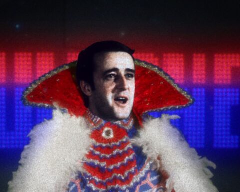 Prime Minister Brian Mulroney appears in a flamboyant Liberace-style outfit with a high collar and white furry trim. The name Mulroney appears behind him in red and blue lights.
