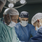 A team of doctors performs a surgery around an operating table.