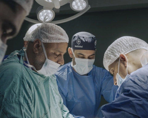 A team of doctors performs a surgery around an operating table.
