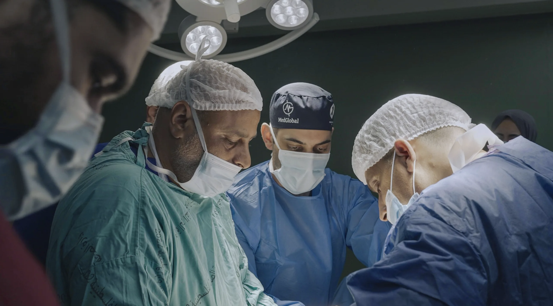 A team of doctors performs a surgery around an operating table.