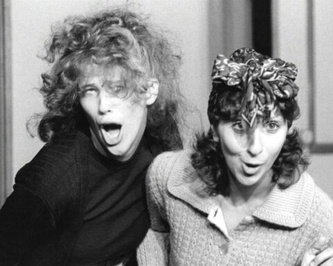 A black and white photo shows young comedians Catherine O'Hara and Andrea Martin making funny faces and being goody during a sketch for SCTV.
