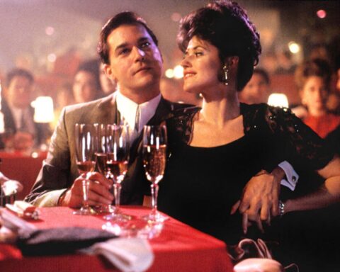 A film still from Goodfellas (1990) depicts actors Ray Liotta and Lorraine Bracco seated at a table in a nightclub.