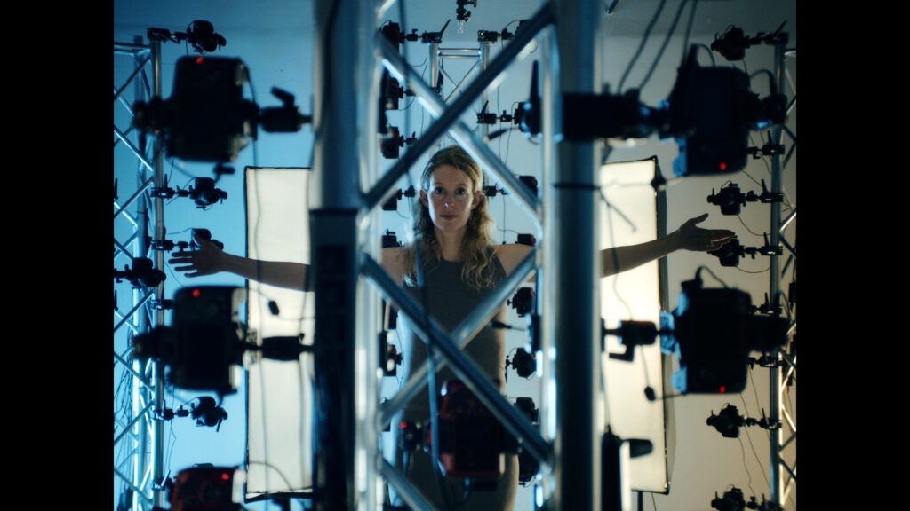 Elizabeth Holmes stands in front of an elaborate set-up of cameras