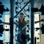 Elizabeth Holmes stands in front of an elaborate set-up of cameras