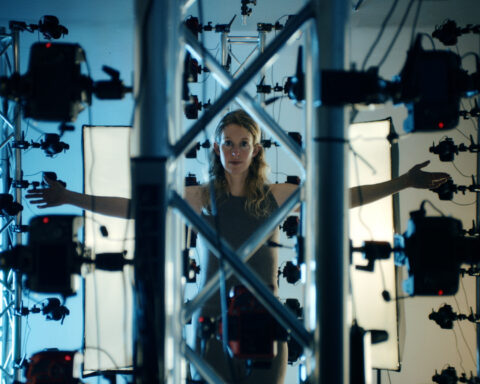 Elizabeth Holmes stands in front of an elaborate set-up of cameras